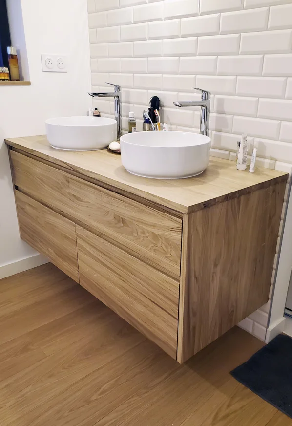 Meuble vasque double suspendu en bois naturel avec vasques blanches rondes, robinetterie chromée et carrelage métro blanc